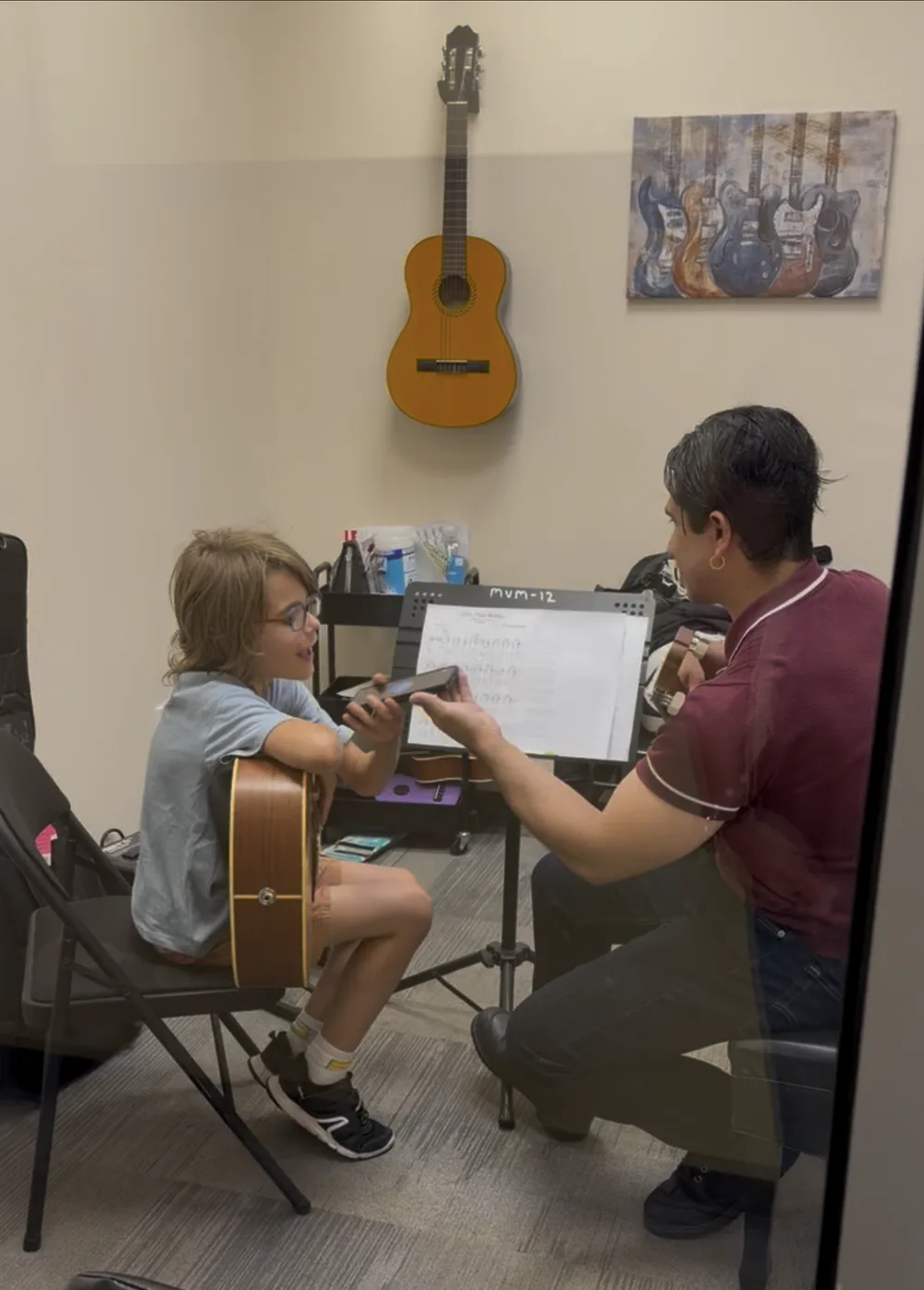 Matheo and Teacher Joseph using live translation during a guitar lesson at Opus 1 Music Studio.
